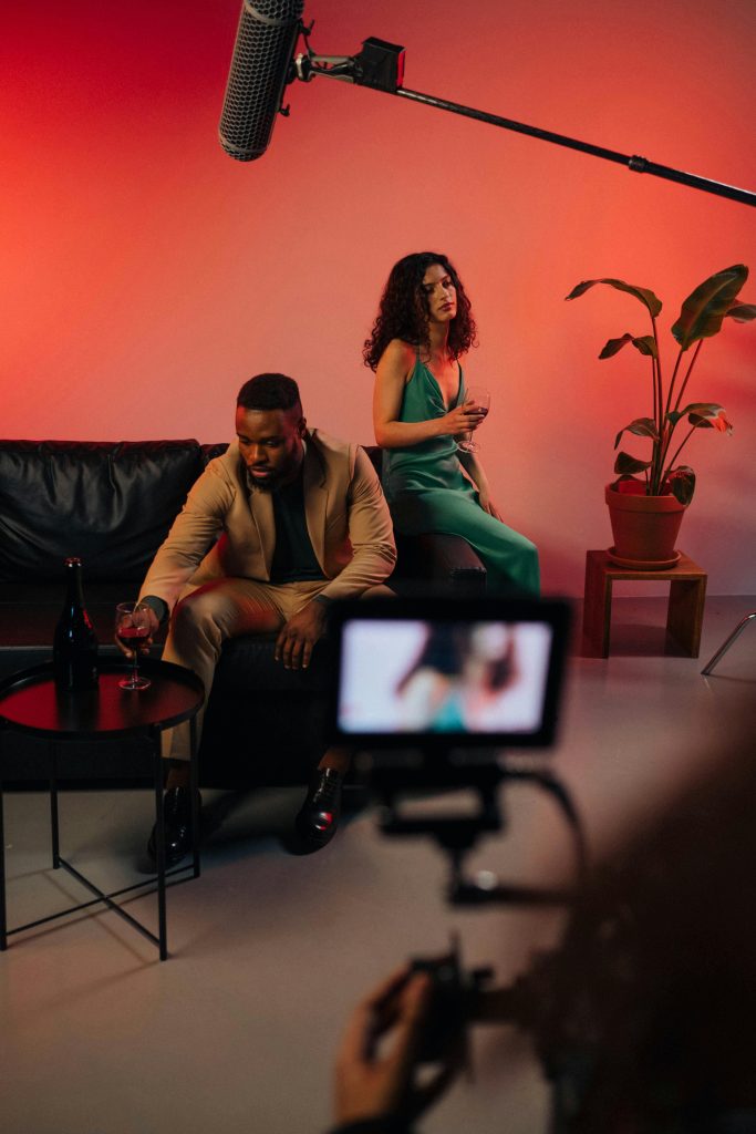 Une caméra filme une scène : un homme et une femme discutent assis sur un canapé