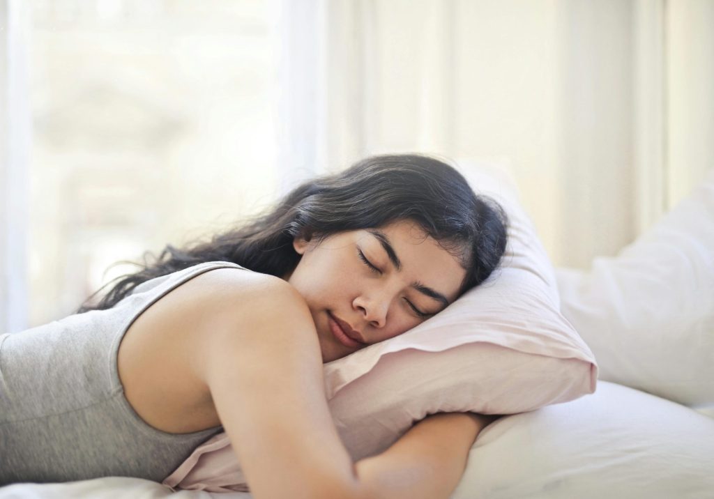 Femme dormant paisiblement sur un oreiller dans un lit.