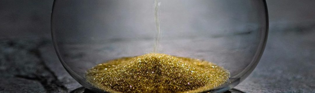 Illustration symbolique d’un sablier rempli de poudre dorée, représentant le temps et l’investissement nécessaires pour produire une vidéo d’entreprise de qualité. L’image évoque la précision, la valeur, et la planification stratégique, essentielles à la réussite d’un projet vidéo avec une agence spécialisée.